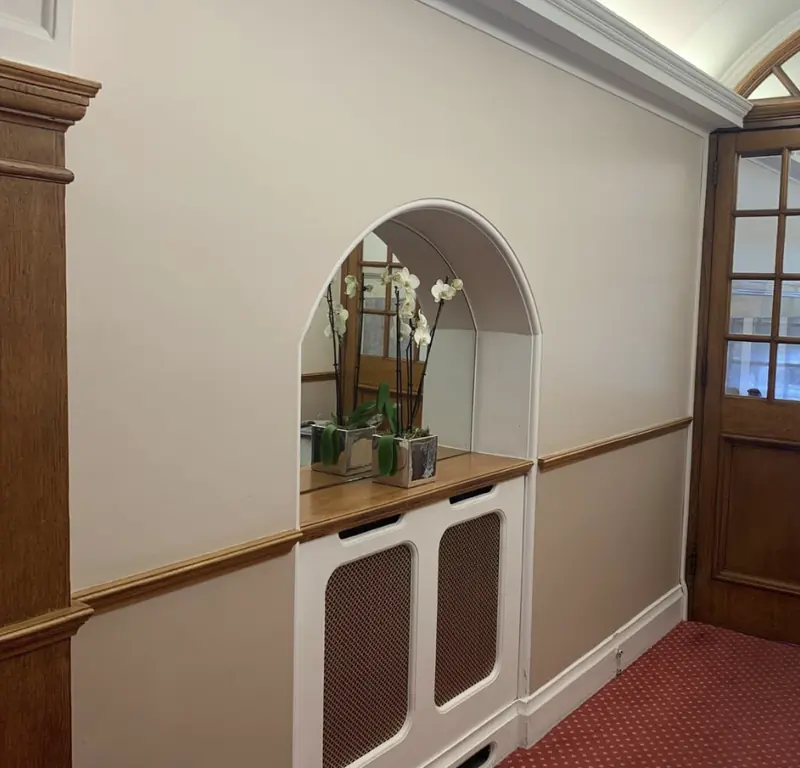 Communal corridor with arched mirror and hardwood doors